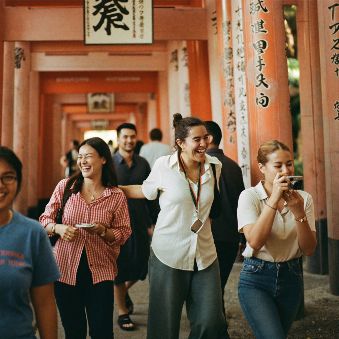 Grupo de viajeros ríe con su guía entre torii